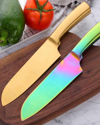 Two knives of stainless steel in gold and multiple colors on a wooden cutting board