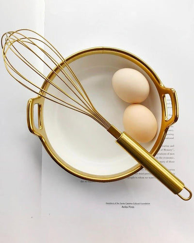Egg beater in gold on a golden pot with 2 eggs