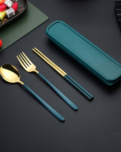 A set of flatware cutlery with golden and turquoise color next to a box. A spoon, a fork and two chopsticks