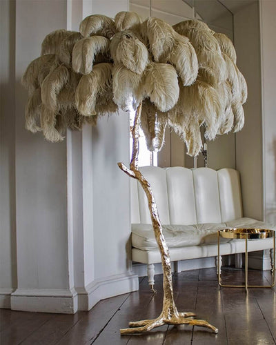 Tree lamp with a golden body and real ostrich feathers in grey in a white living room
