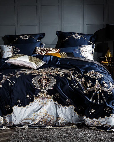 Sevilla bedding in dark blue in front of a grey wall with a lamp next to the bed