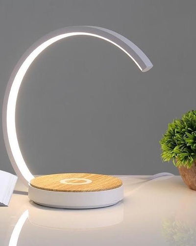 Wireless charging desk lamp made of wood in white color next to a plant on a desk