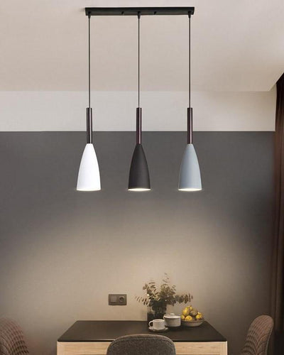 A triplet of ceiling lamps in white, black and grey color hanging on top of a wooden table